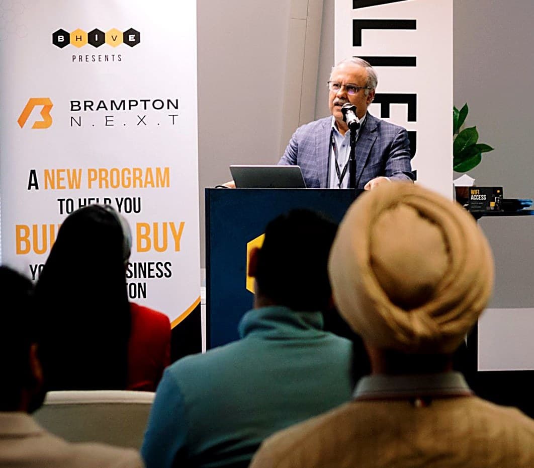 A presenter at Showcase Day in front of a Brampton NEXT banner